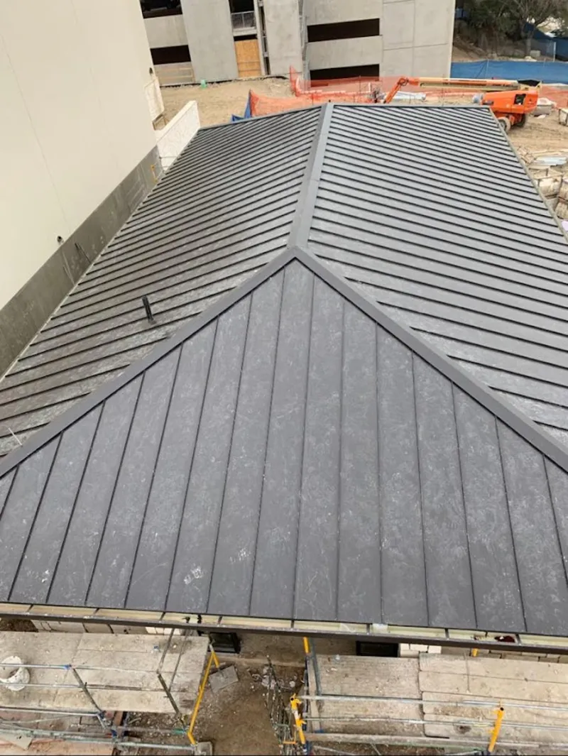 Commercial metal roof construction with crane equipment in Oakland